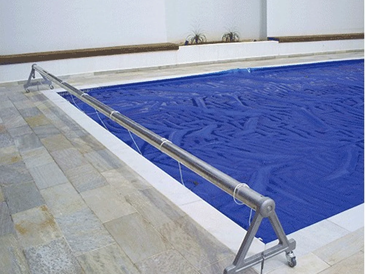 Carrinho enrolador Floty com capa térmica azul na borda de uma piscina