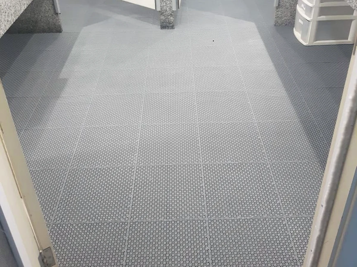 Área de sanitários coberta com Piso Flexível G cinza, da porta ao fundo