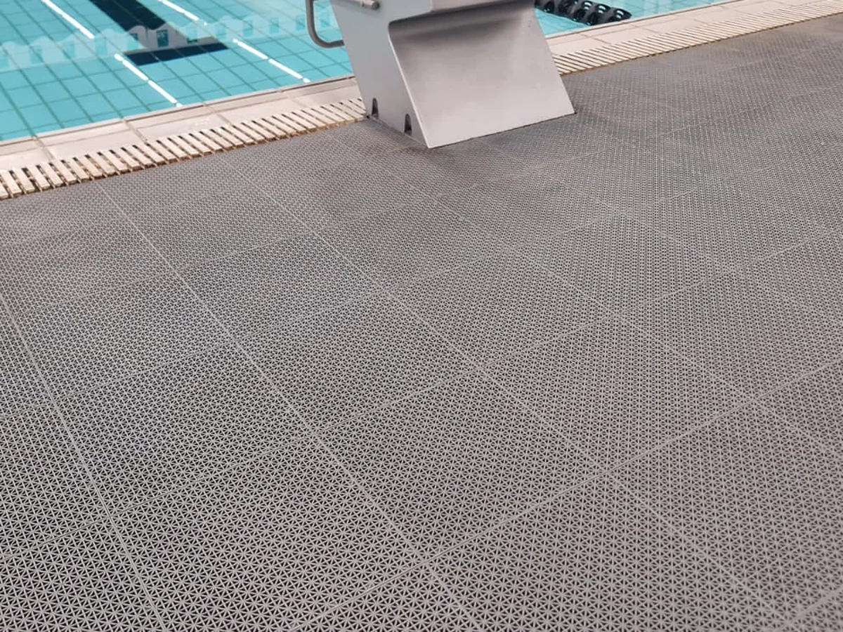Placas cinza de Piso Flexível G instaladas na borda de uma piscina, até a canaleta